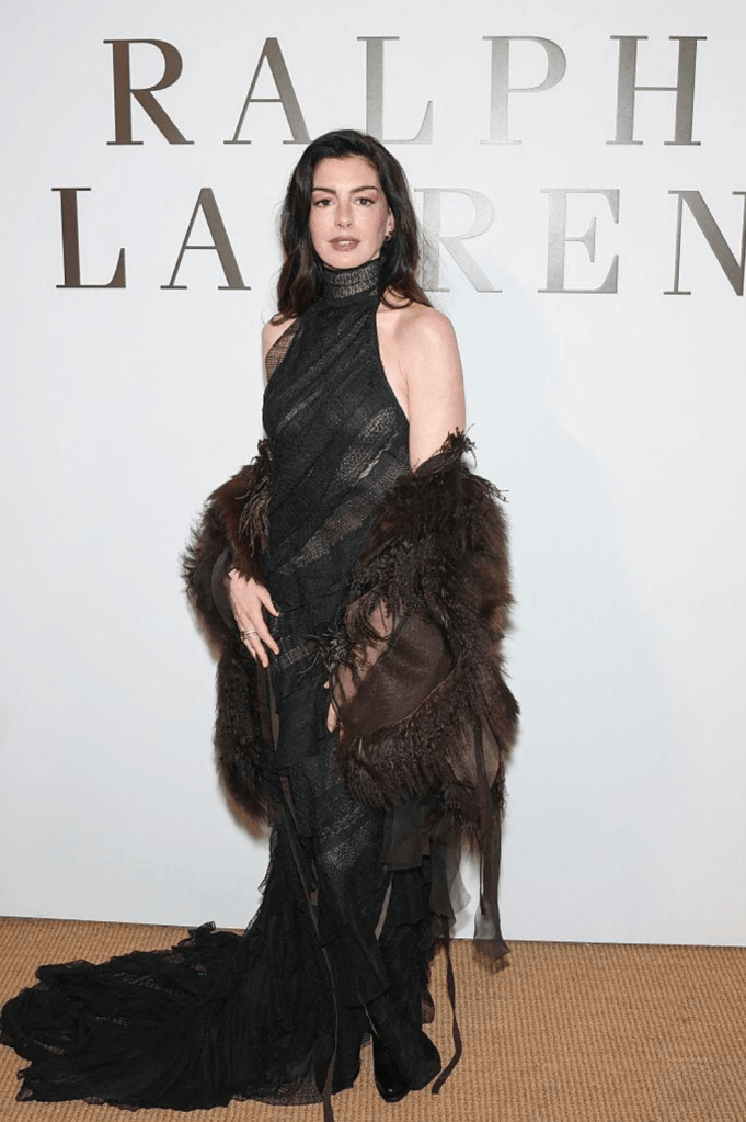 Anne Hathaway in a black lace gown with a fur stole